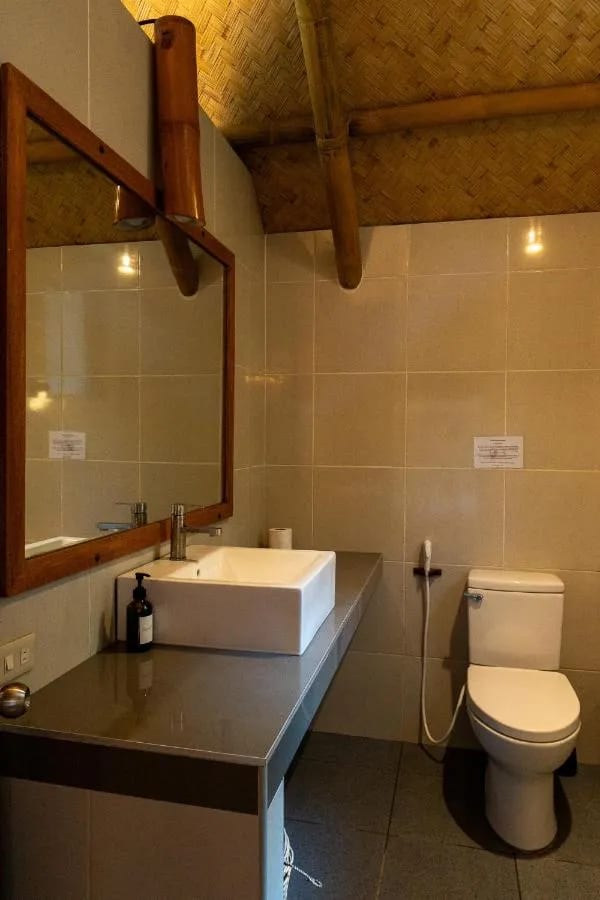 Ein Bad mit Aufsatzwaschbecken auf grauer Platte, holzgerahmtem Spiegel und Toilette