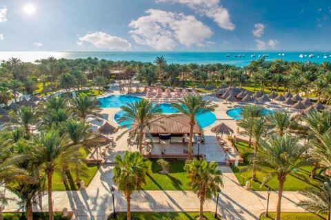 Luftaufnahme des Siva Grand Beach mit seinen Pools zwischen Palmen und dem Roten Meer mit ankernden Booten