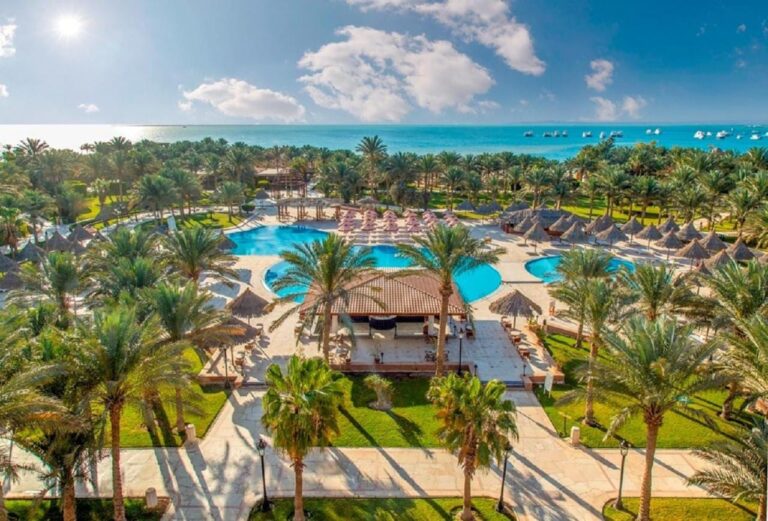 Luftaufnahme des Siva Grand Beach mit seinen Pools zwischen Palmen und dem Roten Meer mit ankernden Booten