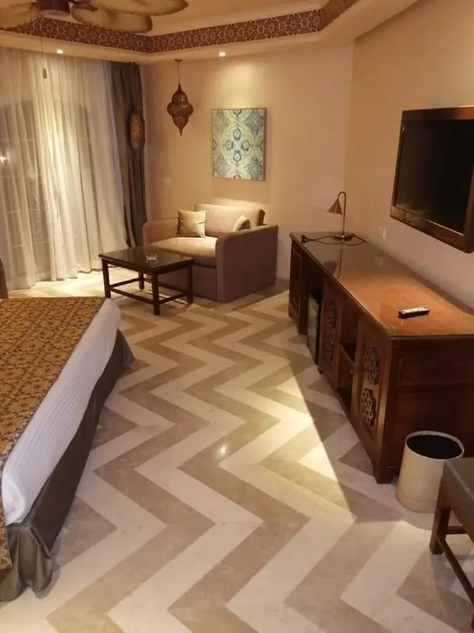 Die Sitzecke eines Zimmers mit Sofa, Holzschreibtisch und Fischgrätboden