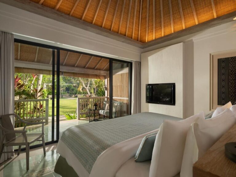 Ein Zimmer unter einer Holzdecke, offen zur Terrasse und zum Rasen
