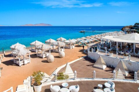 Der Strand des Sunrise Arabian Beach Resorts mit Strohschirmen und Steg, gegenüber der Insel Tiran
