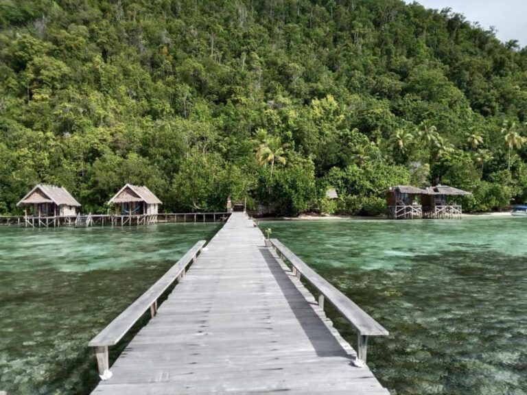 Ein langer Steg mit Bänken, der zwischen den Bungalows des Terimakasih Homestays zum Ufer führt