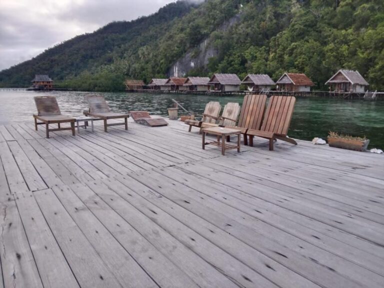 Holzsessel und ein Couchtisch auf einem Steg, mit Blick auf die Klippe und den Wald