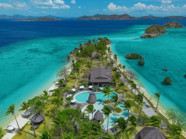 Luftaufnahme des Two Seasons Coron mit Pools und Palmen auf einem schmalen Landstreifen zwischen zwei Stränden