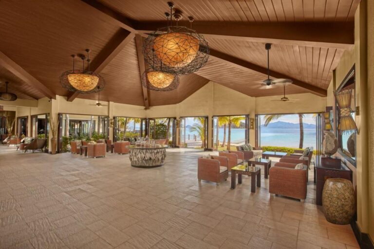 Die Lobby des Two Seasons Coron, offen zum Strand, mit geflochtenen Sesseln und großen Hängeleuchten