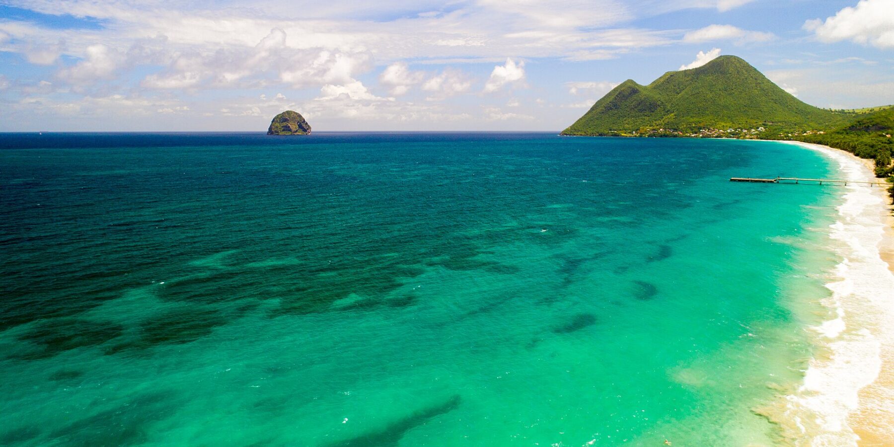 Luftbild des langen Strands von Le Diamant mit türkisem Wasser, draußen der Diamantfelsen und rechts der Morne Larcher, ein grüner Hügel